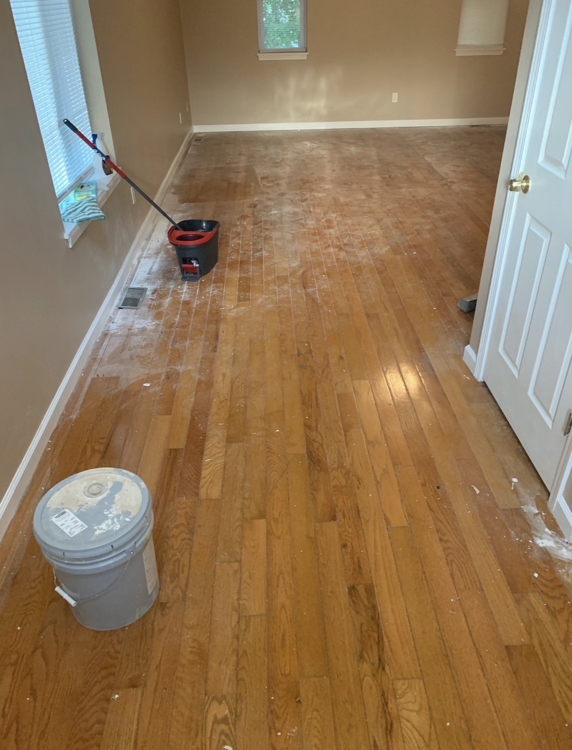 Hardwood floor before QCC post-construction cleaning — drywall dust and debris