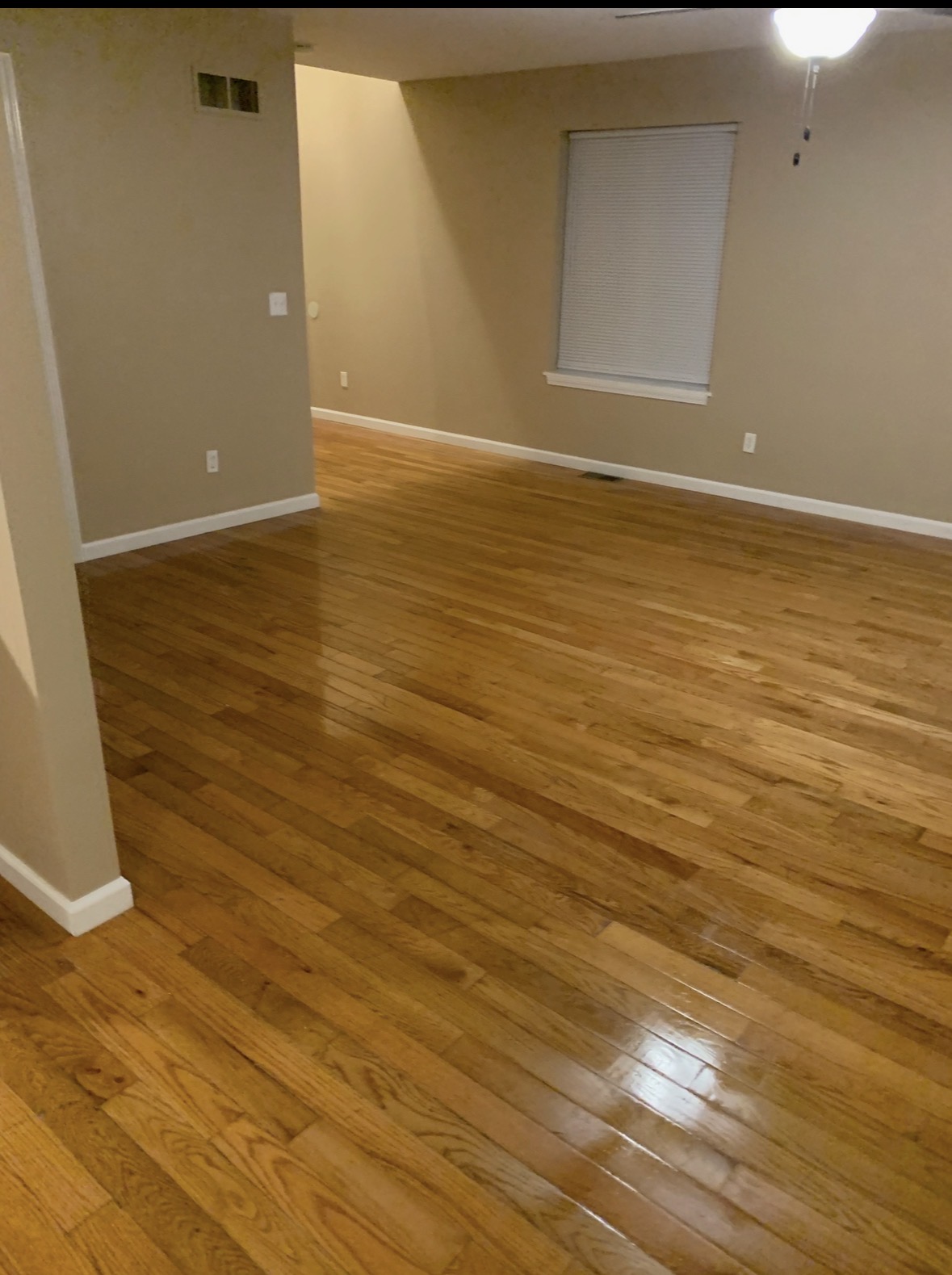 Living room hardwood after QCC post-construction cleaning — glossy and spotless